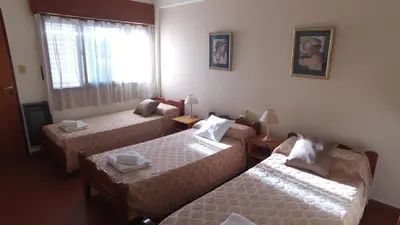 a room with three beds and a window at Hosteria Nilo Azul in Mina Clavero