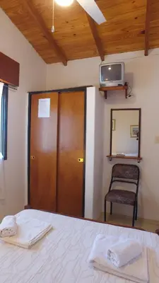 a bedroom with a bed and a chair and a tv at Hosteria Nilo Azul in Mina Clavero