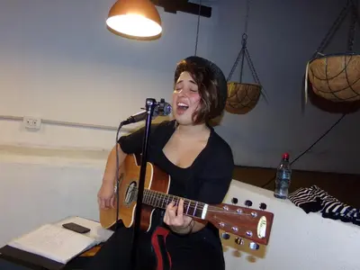 a woman singing into a guitar in a microphone at Hostel & Spa Mediterránea in Cordoba