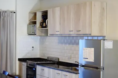 a kitchen with wooden cabinets and a stainless steel refrigerator at Blackstone Country Villages Hotel in Villa General Belgrano
