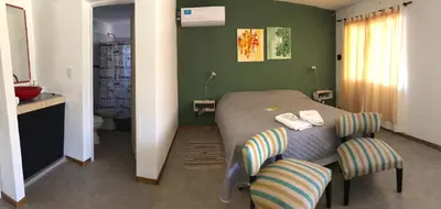 a bedroom with a bed and two chairs at Complejo El Faro in Santa Rosa de Calamuchita