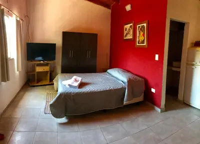 a bedroom with a bed and a red wall at Complejo El Faro in Santa Rosa de Calamuchita
