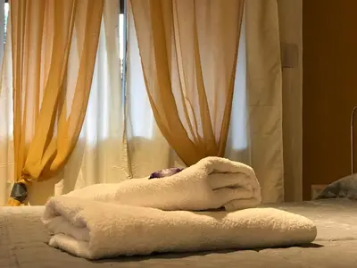 a pile of towels on a bed with curtains at Complejo El Faro in Santa Rosa de Calamuchita