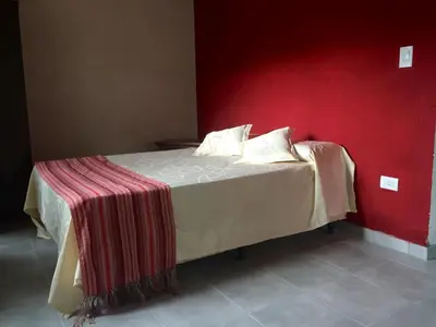 a bed in a room with a red wall at Complejo El Faro in Santa Rosa de Calamuchita