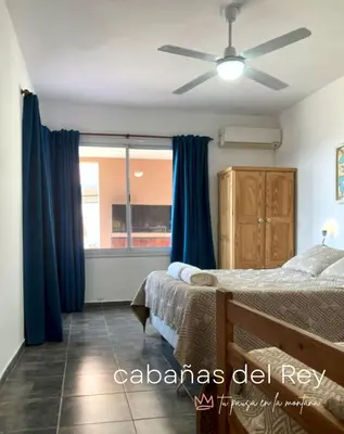 a bedroom with blue curtains and a bed and a window at Cabañas del Rey in Villa Carlos Paz
