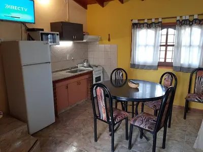 a kitchen with a table and chairs and a white refrigerator at Cabañas Layken in Villa Carlos Paz