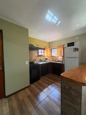 a kitchen with wooden floors and a white refrigerator at Cabañas Layken in Villa Carlos Paz