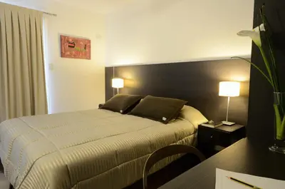 a hotel room with a bed and a desk with two lamps at Corzuelas Aparts - Mina Clavero in Mina Clavero