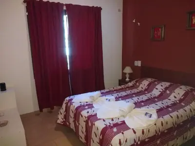 a bedroom with a large bed with red curtains at Cabañas Quinco in Merlo