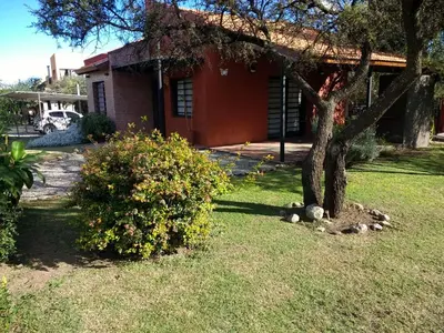 a house with a tree in front of a yard at Cabañas Quinco in Merlo