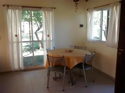 a dining room with a table and chairs and windows at Cabañas Quinco in Merlo
