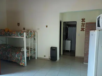 a bedroom with a bunk bed and a room with a refrigerator at Cabañas Quinco in Merlo