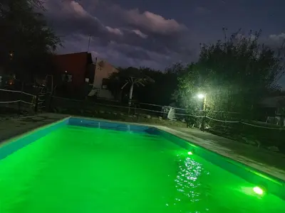 a swimming pool with green water at night at Cabañas Quinco in Merlo