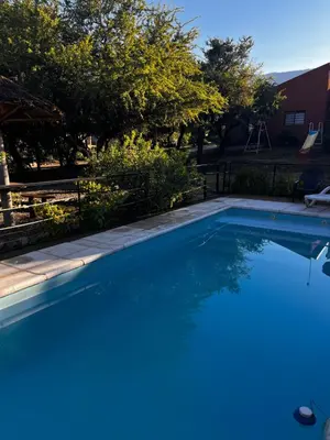 a large blue swimming pool in a yard at Cabañas Quinco in Merlo