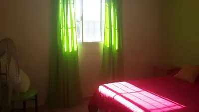 a bedroom with green curtains and a bed and a window at Casas Cordoba in Villa Parque Siquiman