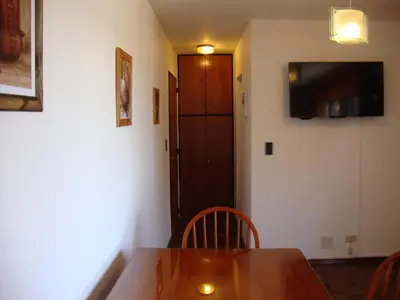 a dining room with a wooden table and a television at Departamento Maipu Cordoba in Cordoba