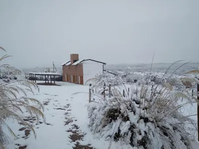 a snow covered field with a house in the background at Complejo Acanto in Villa Carlos Paz