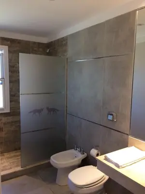 a bathroom with a shower with a toilet and a sink at Parque Los Nogales Apart Hotel in Merlo