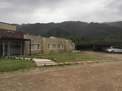 a building with a parking lot with mountains in the background at Parque Los Nogales Apart Hotel in Merlo