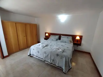 a bedroom with a bed with white sheets and pillows at Hostería Tejas Negras in Mina Clavero