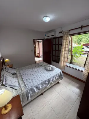 a bedroom with a bed and a large window at Hostería Tejas Negras in Mina Clavero