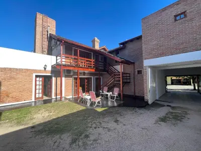 a patio with chairs and a balcony on a brick building at Hostería Tejas Negras in Mina Clavero