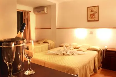 a hotel room with a bed with a bottle of champagne at Hotel Valle Del Sol in Merlo