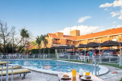 a resort pool with tables and chairs and a building at Hotel Valle Del Sol in Merlo