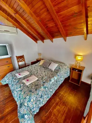 a bedroom with a bed in a room with wooden floors at Sonnen Haus in Villa General Belgrano