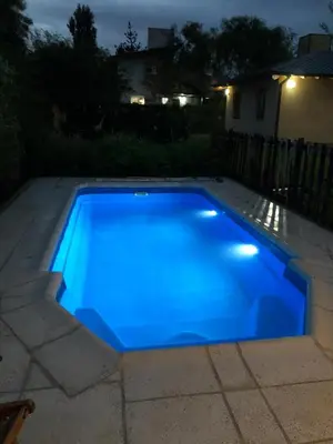 a blue swimming pool in a backyard at night at Sonnen Haus in Villa General Belgrano