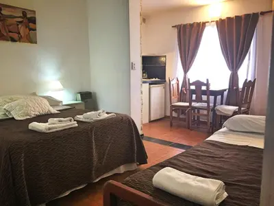 a hotel room with two beds and a dining room at Descanso las Tres Marias Apart Hotel in Villa Carlos Paz
