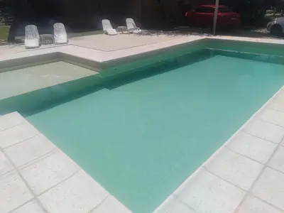 a swimming pool with blue water and chairs in it at Aires de Ambar in Merlo