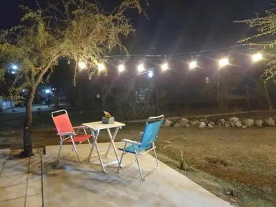 three chairs and a table in a yard at night at Aires de Ambar in Merlo