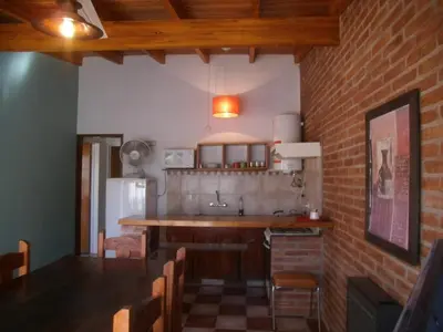 a kitchen with a sink and a counter with chairs at Cabañas Tio Willy in Villa Carlos Paz