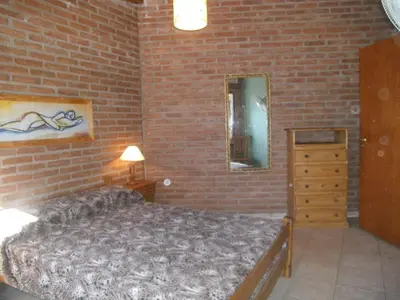 a bedroom with a bed and a brick wall at Cabañas Tio Willy in Villa Carlos Paz