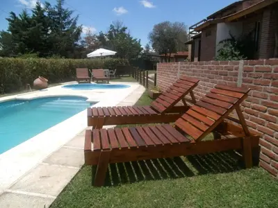 a pair of wooden benches next to a swimming pool at Cabañas Tio Willy in Villa Carlos Paz