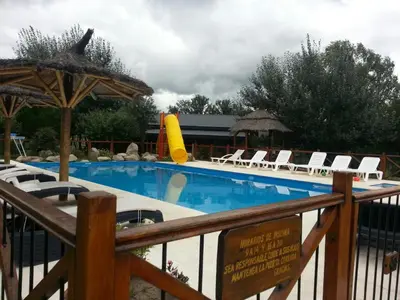 a swimming pool with chairs and a slide at Complejo Tierra Mia in Panaholma
