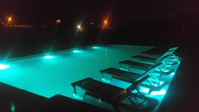 a swimming pool with three chairs and lights at Complejo Tierra Mia in Panaholma