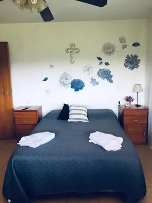 a bed with two pillows and a cross on the wall at Cañada Al Lago in Villa Parque Siquiman
