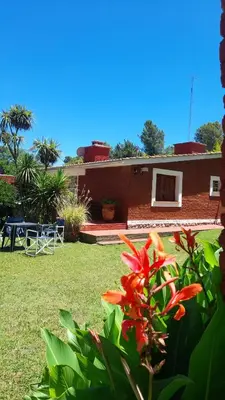 a house with a yard with a table and flowers at Apart Dany in Villa Los Molinos