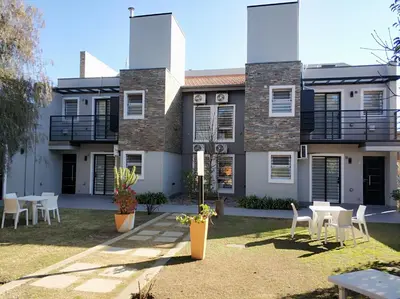 a house with tables and chairs in front of it at Complejo Entre Marte y La Luna in Merlo