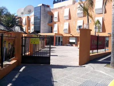 a gate in front of a building with palm trees at Hotel Mónaco in Villa Carlos Paz