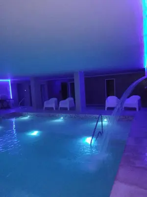 a swimming pool at night with blue and green lights at Hotel Mónaco in Villa Carlos Paz