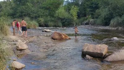 a group of people standing in a river at Cabañas Inti Wara in Los Reartes