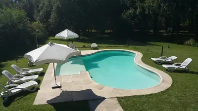 a swimming pool with chairs and an umbrella at Cabañas Inti Wara in Los Reartes