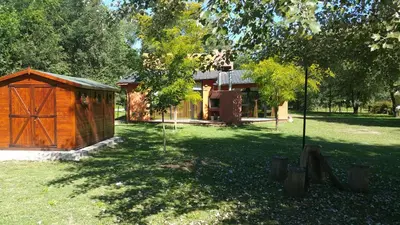 a wooden cabin in a yard with a tree at Cabañas Inti Wara in Los Reartes