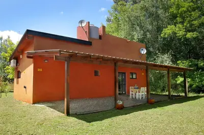 a large orange house with a porch at Cabañas Inti Wara in Los Reartes