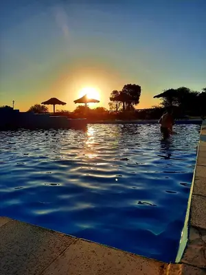 a swimming pool with the sun setting in the background at La Maína Cabañas in San Javier