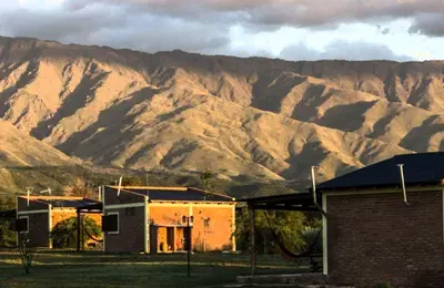a house in front of a mountain range at La Maína Cabañas in San Javier
