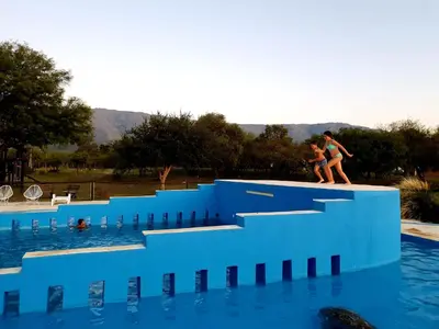 two people walking on the edge of a swimming pool at La Maína Cabañas in San Javier